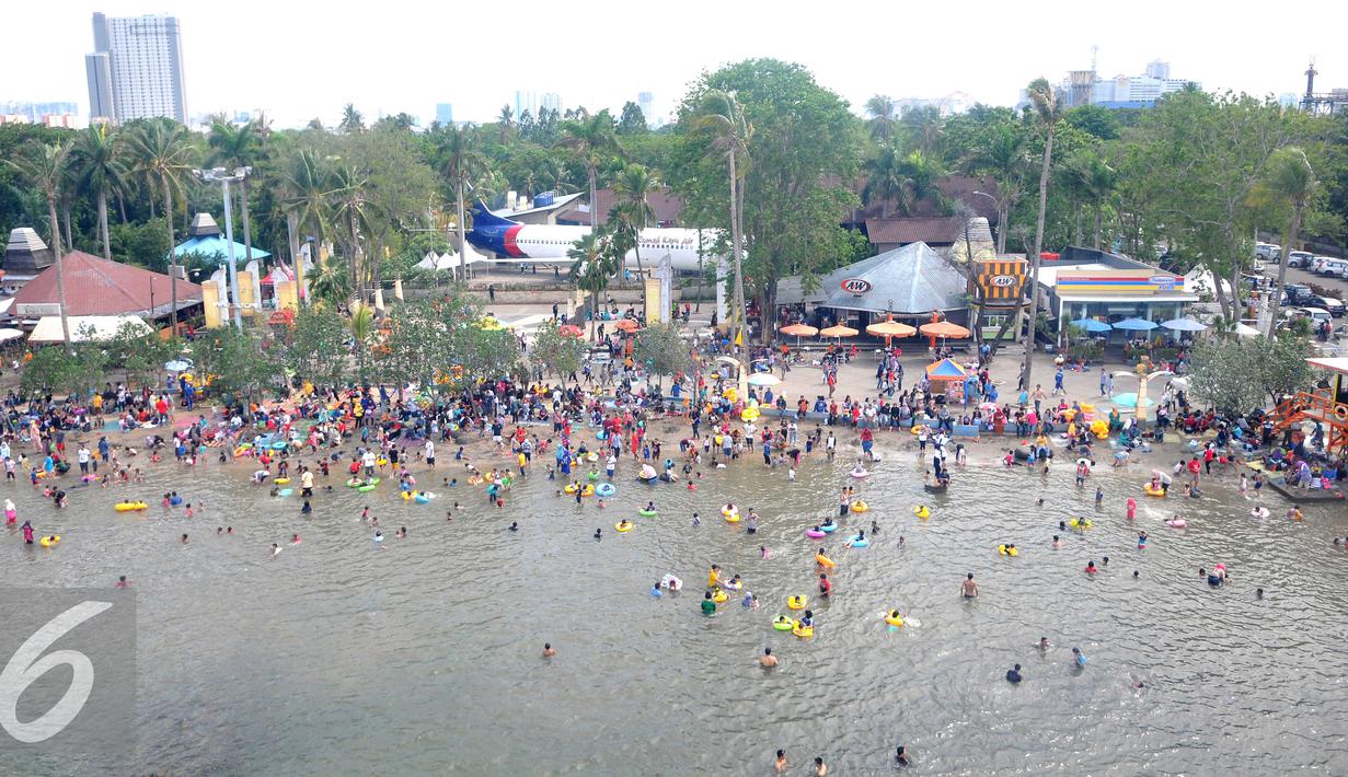 Ribuan pengunjung berenang di Pantai Ancol, Jakarta, Sabtu (26/15). Memasuki libur Tahun Baru sejumlah warga memadati tempat rekreasi di kawasan Ibukota tersebut. (Liputan6.com/Gempur M Surya)