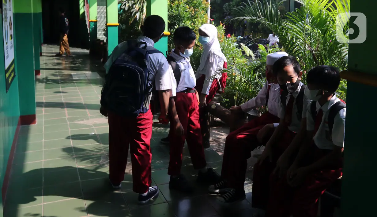 Sejumlah murid SDN Kota Baru berbincang di depan kelas saat pelaksanaan ujian penilaian akhir sekolah di SDN Kota Baru 3 Bekasi, Jawa Barat, Senin (8/6/2021). Ujian dilaksanakan dengan pembatasan 50 persen jumlah murid tiap ruangan. (Liputan6.com/Herman Zakharia)