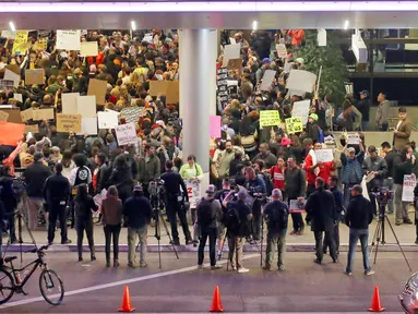Ratusan massa berkumpul di Terminal Internasional Tom Bradley, Bandara LAX menggelar aksi protes, di Los Angeles, Sabtu (28/1). Mereka mengecam kebijakan Donald Trump yang melarang warga dari 7 negara mayoritas muslim, masuk ke AS. (AP Photo/Reed Saxon)