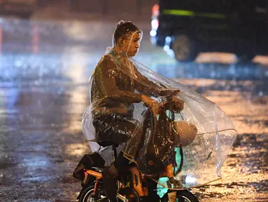 Seorang pria mengendarai sepeda di bawah hujan di Distrik Chaoyang, Beijing, China (12/8/2020). Badan meteorologi Beijing mengeluarkan peringatan siaga kuning untuk hujan badai. (Xinhua/Ju Huanzong)