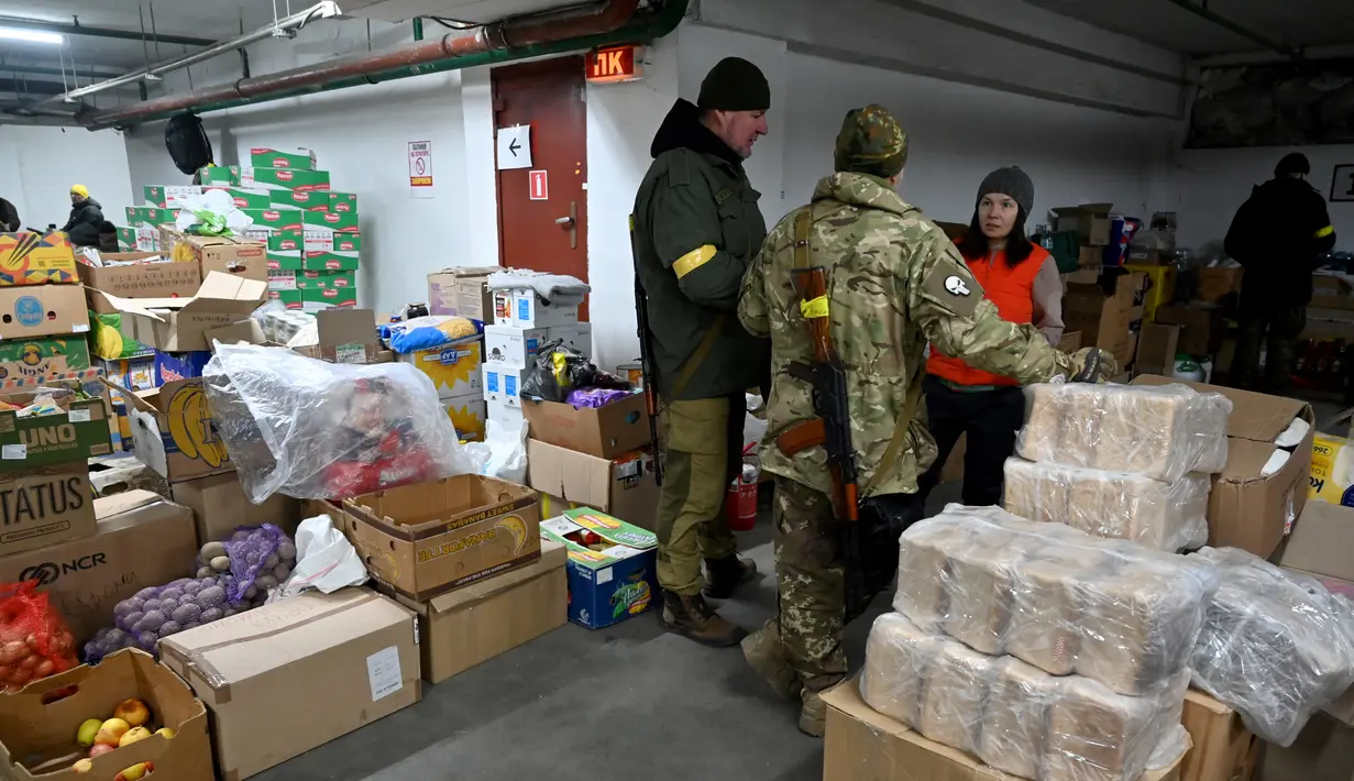 Prajurit Pasukan Pertahanan Teritorial Ukraina, cadangan militer Angkatan Bersenjata Ukraina, menerima makanan di gudang di garasi bawah tanah yang telah diubah menjadi pangkalan pelatihan dan logistik di Kiev, pada Jumat (11/3/2022). (Sergei SUPINSKY / AFP)