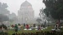 Warga berlatih yoga di Lodhi Gardens di tengah kondisi kabut asap tebal di New Delhi (30/10). Tingkat kabut melonjak selama musim dingin di Delhi, ketika kualitas udara sering melampaui tingkat aman Organisasi Kesehatan Dunia. (AFP Photo/Dominique Faget)