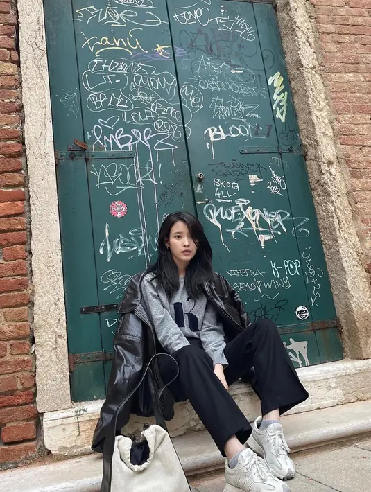 IU sedang duduk di depan pintu yang tercorat-coret.  [Foto: Instagram/ dlwlrma]