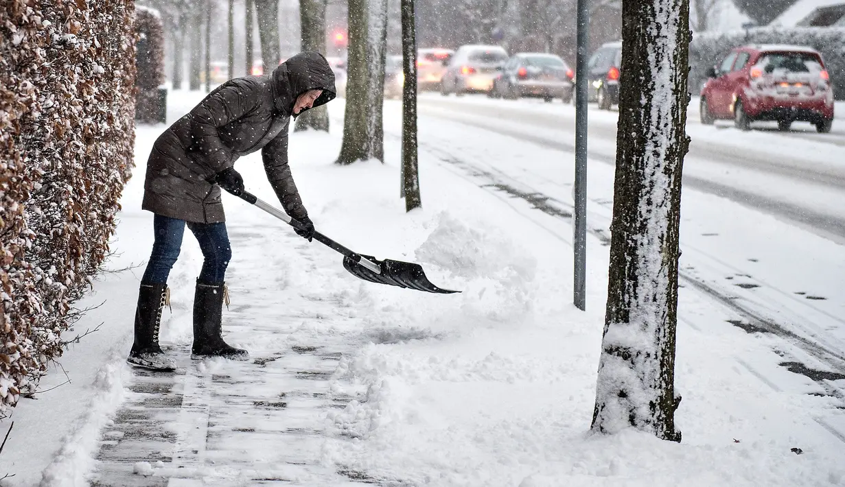 Seorang wanita membersihkan trotoar dari salju tebal di Aalborg, Denmark, Selasa (27/2). Cuaca dingin yang dijuluki "The Beast from the East" membuat suhu di sebagian Eropa turun. (AFP PHOTO/Scanpix DAN Ritzau SCANPIX/Henning Bagger/Denmark OUT)
