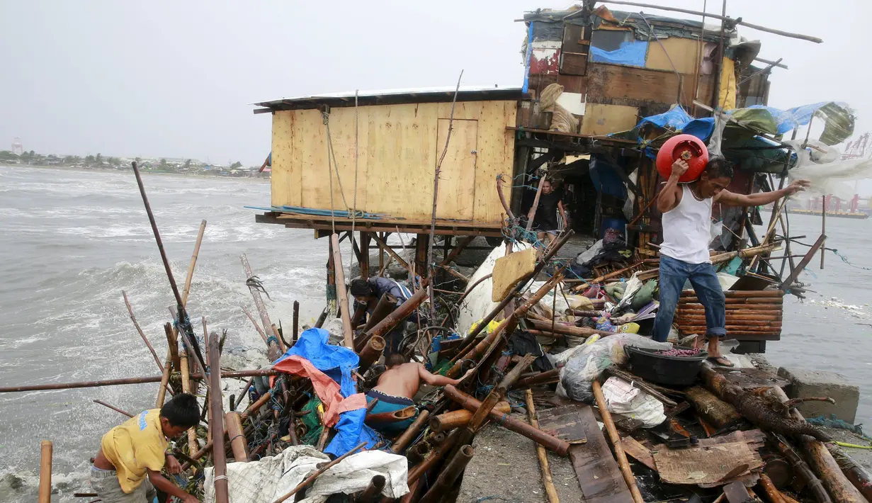 Keluarga Taroyo yang tinggal di sepanjang pantai Teluk Manila mencari barang yang bisa diselamatkan setelah rumah mereka rusak akibat Topan Koppu, Minggu (18/10). Topan Koppu melanda Filipina timur laut dan merusak rumah-rumah. (REUTERS/Romeo Ranoco)