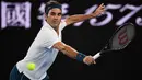 Petenis Swiss, Roger Federer melakukan servis ke arah lawannya Taylor Fritz dari AS dalam babak 32 besar Australia Terbuka di Melbourne, Jumat (18/1). Federer melaju mulus ke babak 16 besar setelah menang tiga set langsung 6-2 7-5 6-2. (WILLIAM WEST/AFP)