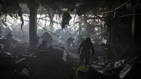 Petugas pemadam kebakaran dan prajurit Ukraina mencari orang-orang di bawah puing-puing dalam pusat perbelanjaan setelah serangan di Kiev, Ukraina, Senin (21/3/2022). Delapan orang tewas dalam serangan tersebut. (AP Photo/Felipe Dana)