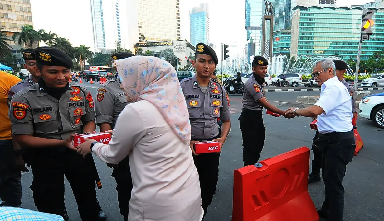 Direktur Program TKN Jokowi-Ma'ruf Amin, Aria Bima (kemeja putih) bersama relawan TKN  membagikan makanan berbuka puasa kepada aparat kepolisian yang melakukan penjagaan di kawasan Bundaran HI, Jakarta, Jumat (24/5/2019). (Liputan6.com/Angga Yuniar)