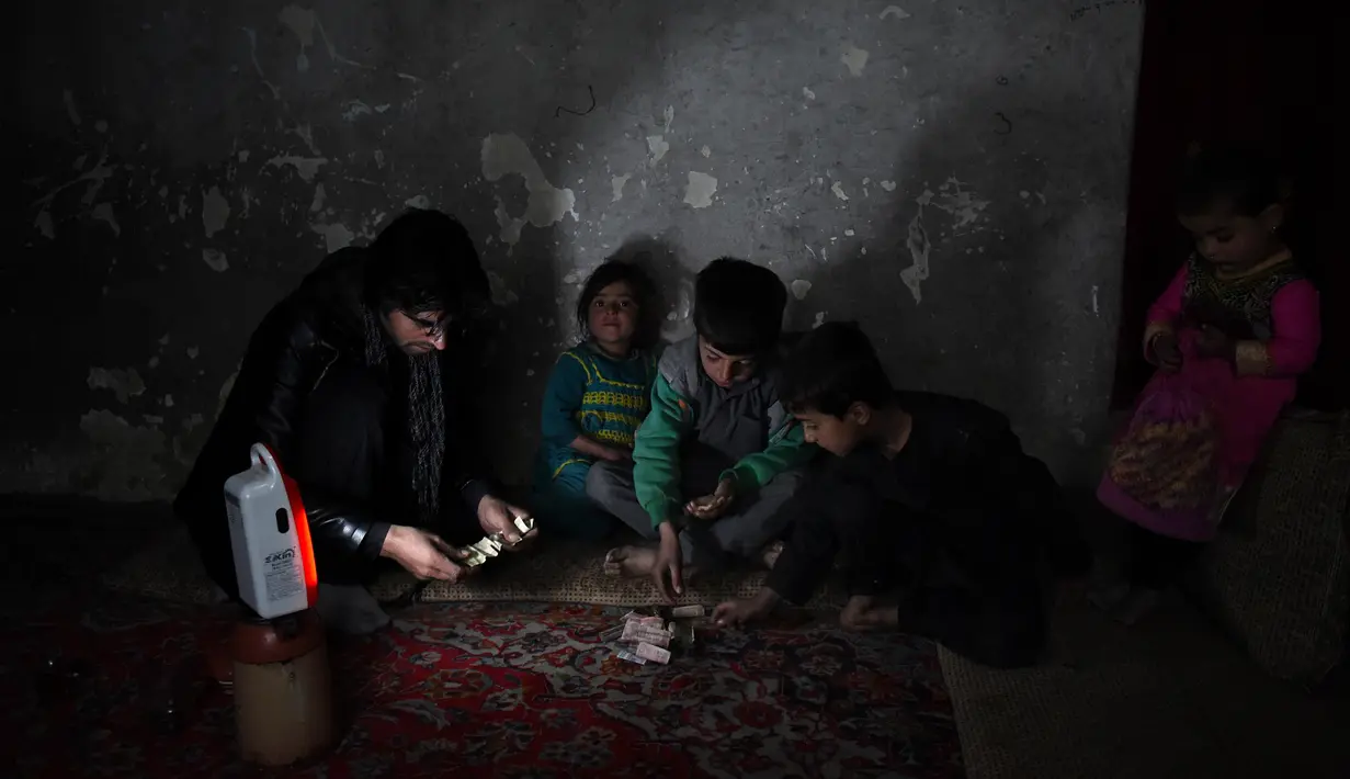 Bocah penjual air, Afghan Zilgai (9), bersama ayah dan saudaranya menghitung penghasilannya di rumahnya di Kabul, 20 Februari 2016. Afghan setiap hari menjual air kepada para peziarah dengan penghasilan 1,5 USD/hari. (AFP PHOTO/Wakil KOHSAR)