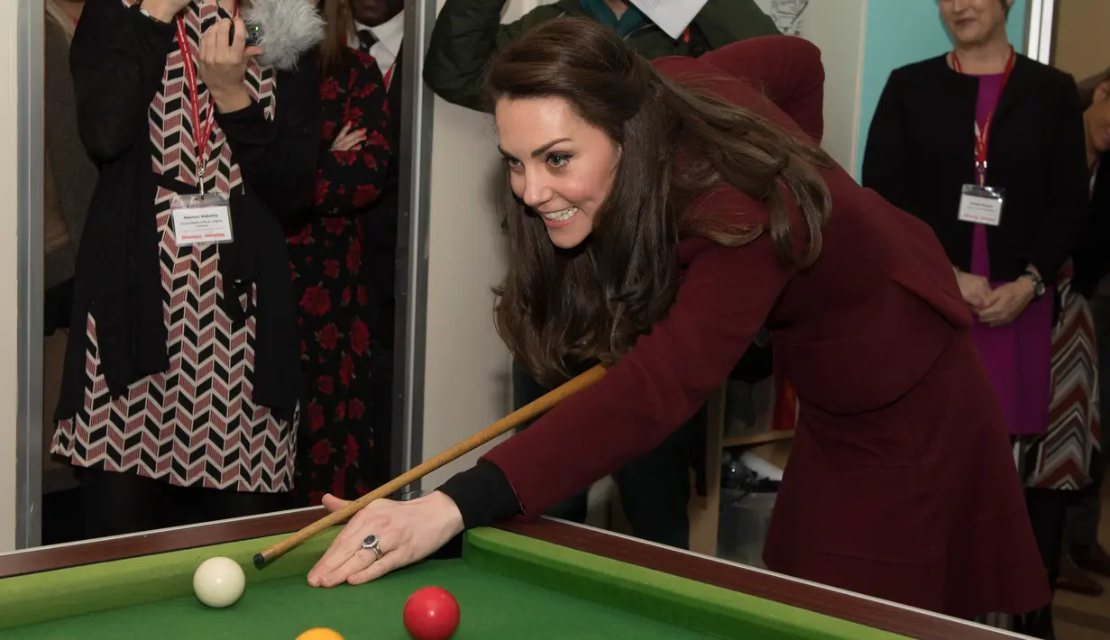 Kate Middleton bersiap memukul bola ketika bermain biliar saat kunjungannya ke MIST, sebuah tempat kesehatan mental bagi anak di Pontypool, Wales, Inggris (22/2). Kate terlihat menikmati permainan biliar tersebut. (AFP Photo / Pool / Paul Edwards)