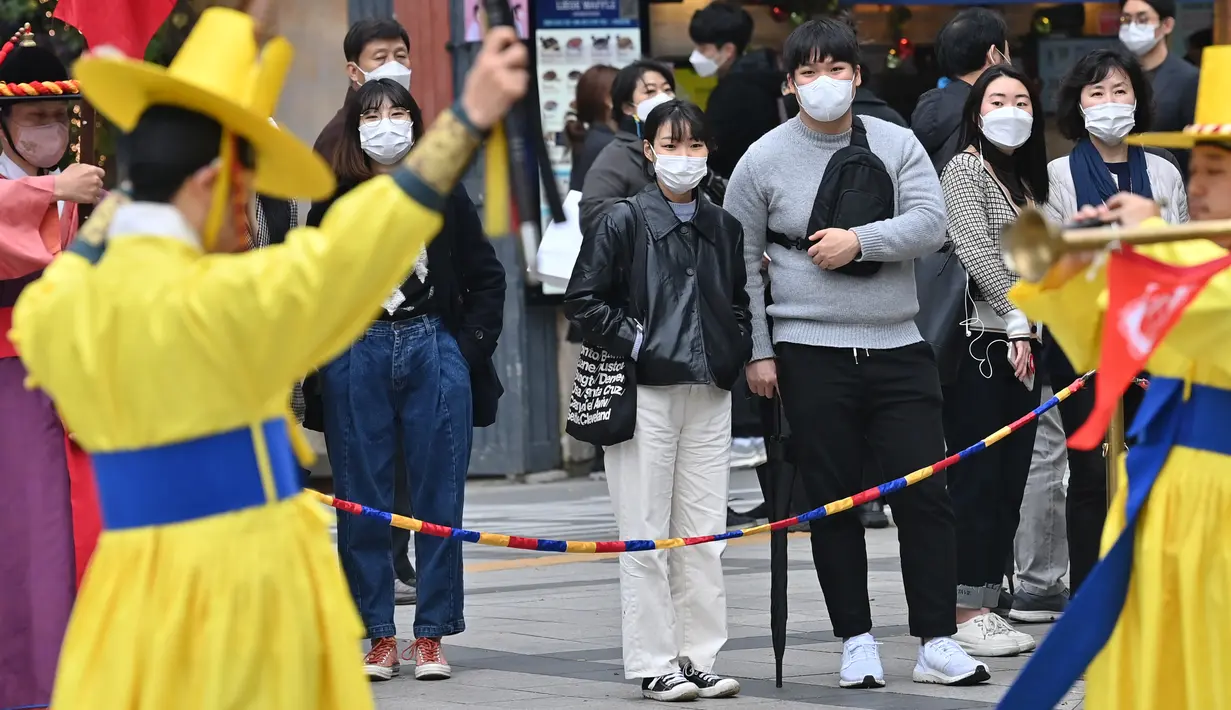 Pengunjung yang mengenakan masker menyaksikan upacara pergantian penjaga istana di gerbang utama Istana Deoksugung di Seoul, Rabu (18/11/2020). Upacara Pergantian Penjaga Kerajaan diadakan mulai hari Selasa hingga Minggu, sebanyak tiga kali sehari (11:00, 14:00, 15:30). (Jung Yeon-je AFP)