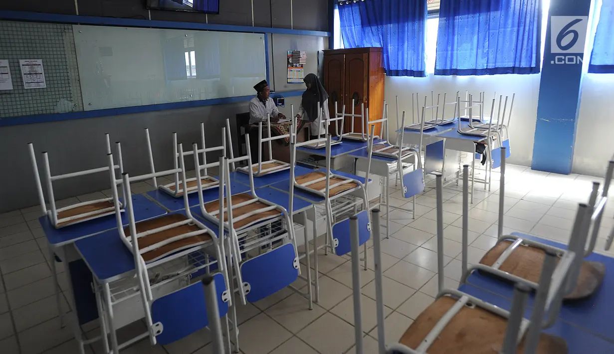 Guru berbincang dengan seorang siswa di ruang kelas yang kosong di Mts Annajah, Petukangan, Jakarta, Senin (5/8/2019). Masih padamnya listrik di sejumlah kawasan Jakarta membuat kegiatan belajar mengajar terganggu hingga memaksa pihak sekolah memulangkan siswa lebih awal. (merdeka.com/Arie Basuki)