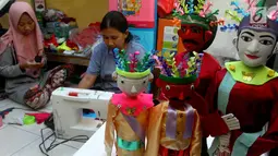 Perajin menyelesaikan pembuatan miniatur ondel-ondel di rumah produksi Kramat Jati, Jakarta, Senin (23/6/2019). Perajin dapat memproduksi 50  hingga 80 miniatur ondel-ondel dalam sebulan. (merdeka.com/Arie Basuki)