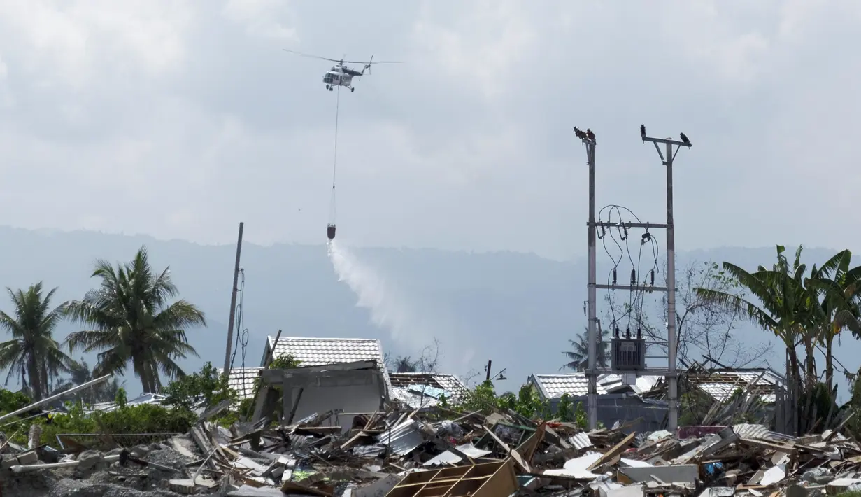 Helikopter BNPB menyemprotkan cairan disinfektan ke kawasan terdampak likuifaksi di Petobo dan Balaroa, Palu, Sulawesi Tengah, Kamis (18/10). Likuifaksi adalah fenomena yang terjadi ketika tanah jenuh atau agak jenuh kehilangan kekuatan. (Yusuf Wahil/AFP)