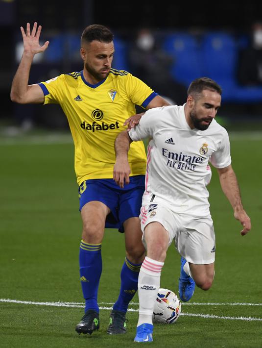 Pemain Cadiz Juan Cala (kiri) memperebutkan bola dengan pemain Real Madrid Dani Carvajal pada pertandingan La Liga Spanyol di Stadion Ramon Carranza, Cadiz, Spanyol, Rabu (21/42021). Real Madrid menang 3-0. (AP Photo/Jose Breton)
