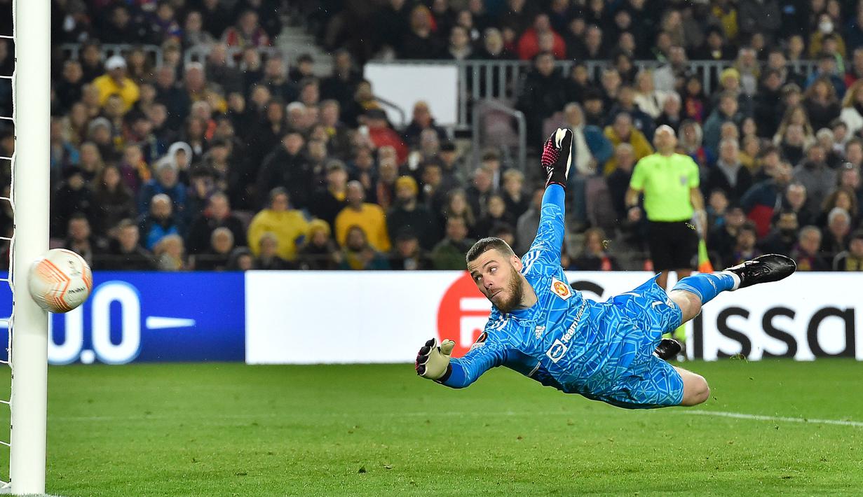 Penjaga gawang MU, David De Gea berusaha menghalau bola tendangan dari pemain Barcelona dalam pertandingan leg pertama play-off babak gugur Liga Europa 2022/2023 yang berlangsung di Camp Nou, Jumat (17/2/2023). (AFP/Pau Barrena)