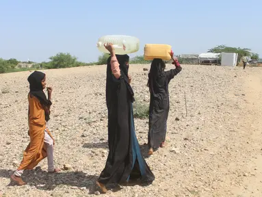 Perempuan pengungsi internal Yaman berjalan menuju tempat penampungan air untuk mengisi jeriken mereka di Distrik Abs, Provinsi Hajjah, Yaman, 10 Oktober 2026. (Essa Ahmed/AFP)