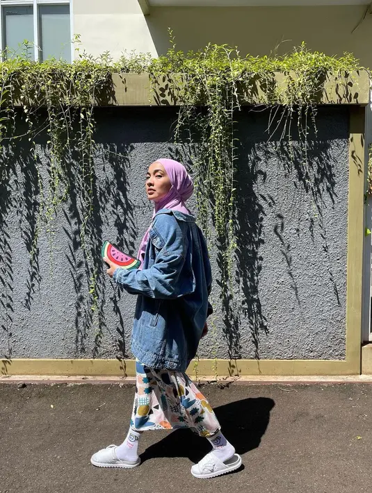 Untuk gaya eksploratif, Tika kenakan hijab instan dengan dress bermotif dan long denim jacket. [@tikabravani]