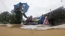 Sebuah keluarga mengarungi banjir setelah mengevakuasi rumah mereka di daerah banjir di Yong Peng, negara bagian Johor Malaysia, Sabtu (4/3/2023). Departemen meteorologi memperingatkan lebih banyak hujan dalam beberapa hari mendatang, terutama sebagian besar di negara bagian selatan. (Photo by Mohd RASFAN / AFP)