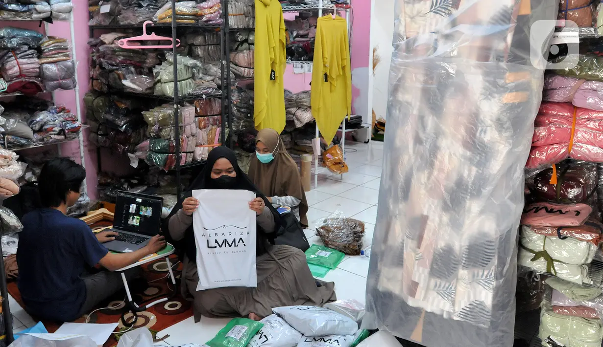 Pekerja membungkus baju muslim pesanan secara online di home industri busana muslim Albarizk UMMA di kawasan Beji, Depok, Selasa (12/4/2022). Mendekati lebaran, penjualan jilbab dan busana musim secara online meningkat 100 persen dibandingkan tahun lalu saat masa pandemi. (merdeka.com/Arie Basuki)
