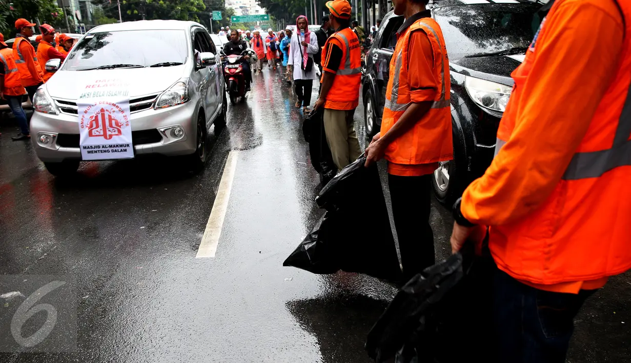 Kendaraan peserta aksi damai 2 Desember melewati pasukan oranye (petugas kebersihan) yang disiagakan di kawasan Monas, Jakarta, Jumat (2/12). Pasukan oranye dibekali kantong plastik besar untuk memungut sampah yang berserakan. (Liputan6.com/Johan Tallo)