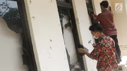Pekerja membersihkan sisa pecahan kaca di salah satu bagian gedung Bawaslu akibat kericuhan massa aksi di perempatan Jalan MH Thamrin, Jakarta, Kamis (23/5/2019). Sebelumnya, aksi unjuk rasa yang dilakukan massa pada Rabu (23/5) berakhir ricuh. (Liputan6.com/Helmi Fithriansyah)