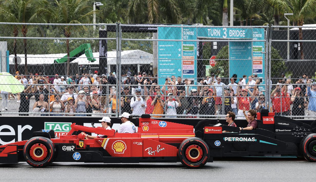 Pembalap Ferrari, Charles Leclerc bersama Lewis Hamilton mengikuti parade pembalap menggunakan mobil lego sebelum balapan Formula 1 GP Miami 2025 yang berlangsung di Sirkuit Autodromo, Miami, Florida, Minggu (04/05/2025) waktu setempat. (AFP/Charly Triballeau)