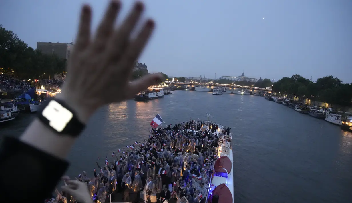 Ribuan atlet berparade menggunakan kapal di atas Sungai Seine dalam upacara pembukaan Olimpiade Paris 2024 pada Jumat malam waktu setempat meskipun diguyur hujan deras yang tak henti-hentinya. (AP Photo/Christophe Ena)