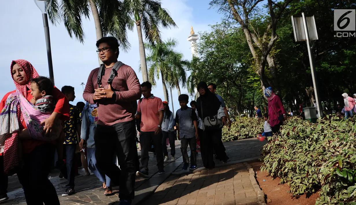 Pengunjung berjalan di kawasan Monumen Nasional, Jakarta, Senin (25/12). Libur perayaan Natal dimanfaatkan warga untuk berwisata di kawasan Monumen Nasional. (Liputan6.com/Helmi Fithriansyah)