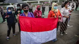 Massa dari Jaringan Pembela Hak Perempuan Korban Kekerasan Seksual membawa bendera Merah Putih di depan Gedung DPR, Jakarta, Rabu (22/12/2021). Mereka mendesak DPR mengesahkan rancangan undang-undang Tindak Pidana Kekerasan Seksual (RUU TPKS) sebagai RUU Inisiatif DPR RI (Liputan6.com/Faizal Fanani)