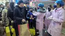 Petugas memeriksa suhu tubuh seorang penumpang di Stasiun Kereta Api Yingtan di Nanchang di Provinsi Jiangxi Tengah, China (22/1/2020). Sebanyak 17 orang meninggal akibat terinfeksi virus corona. (AFP Photo/STR)