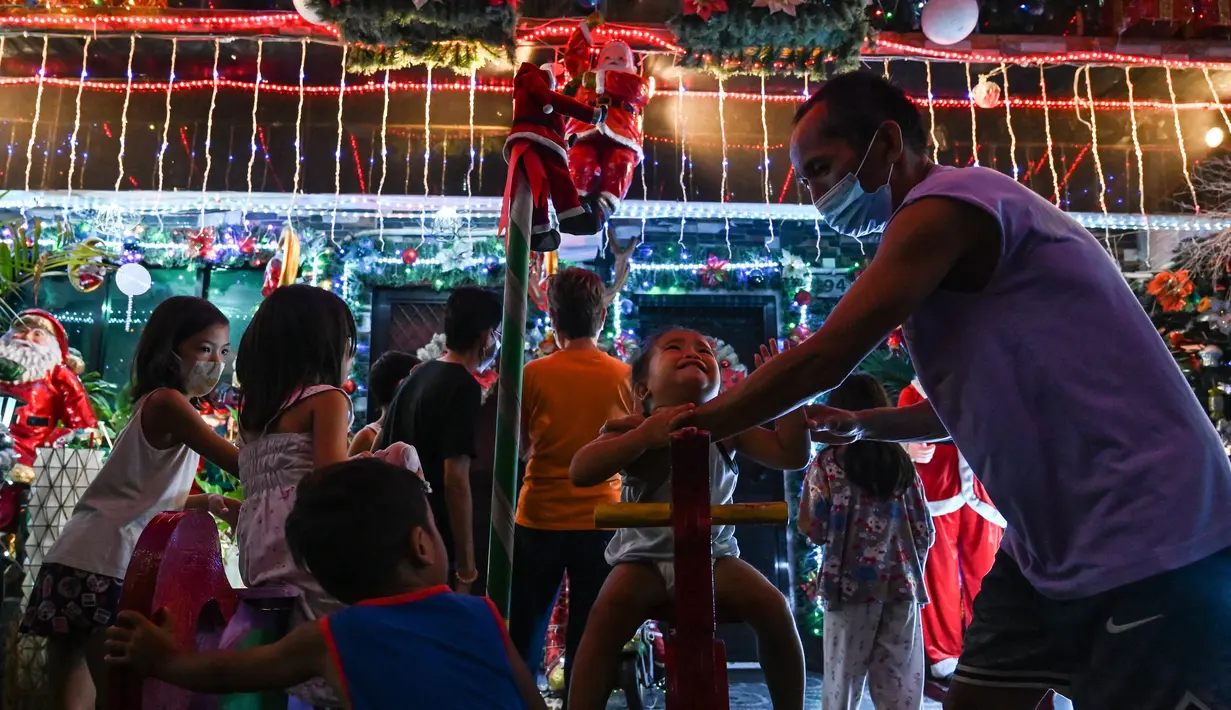 Anak-anak bermain di luar rumah bertema Natal di Manila (21/12/2022). Perayaan Natal tinggal menghitung hari, warga Manila antusias mengunjungi rumah yang didekor dengan ornamen dan hiasan Natal itu. (AFP/Jam Sta Rosa)