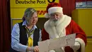 Seorang pria berkostum Sinterklas dan karyawan dari layanan pos Jerman, Deutsche Post membaca daftar keinginan seorang anak di Kantor Pos Natal di Himmelpfort, Jerman pada 19 Desember 2018. (Tobias SCHWARZ/AFP)