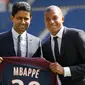 Penyerang PSG, Kylian Mbappe dan CEO Nasser Al-Khelaifi menunjukkan jersey klub PSG usai resmi bergabung dalam konferensi pers bersama PSG di Paris, (6/9). (AP Photo / Christophe Ena)