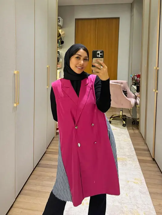 Hijab tersebut kemudian dipadukan dengan long sleeve top di bawah vest berwarna fuschia. Untuk bawahan, Nisya melengkapi gayanya dengan celana jeans.  [@raffinagita1717/@nissyaa/@syahnazs].