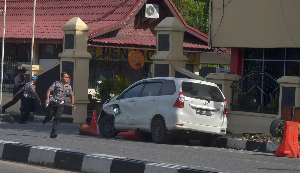 Petugas kepolisian mengamankan mobil yang digunakan terduga teroris setelah serangan di luar markas polisi di Pekanbaru, Riau (16/5). Dalam serangan tersebut satu perwira tewas dan dua lainnya terluka. (AFP Photo/Dedy Sutisna)