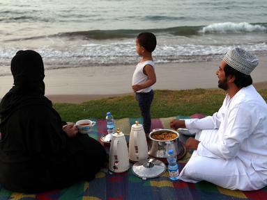 Sebuah keluarga Oman berkumpul untuk berbuka puasa di pantai di Muscat selama bulan suci Ramadhan pada 12 April 2022. Umat islam di seluruh dunia saat ini tengah melaksanakan bulan Ramadhan dan berpuasa selama satu bulan. (MOHAMMED MAHJOUB / AFP)