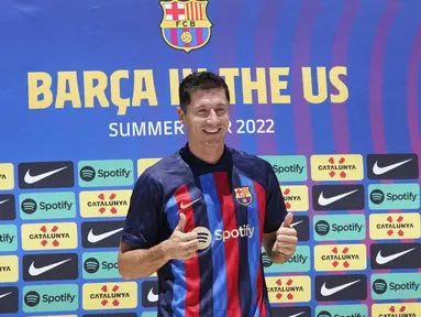 Robert Lewandowski mengenakan jersey saat diperkenalkan sebagai pemain baru Barcelona di Fort Lauderdale, Florida, Rabu (20/7/2022). Senyum lebar terpancar dari wajahnya yang menyapa para penggemar yang hadir dalam acara tersebut. (AP Photo/Marta Lavandier)