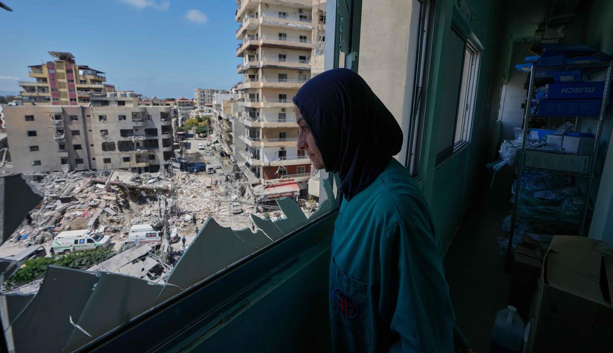 Seorang perawat melihat melalui jendela yang pecah di Rumah Sakit Jabal Amel ke dalam bangunan yang hancur akibat serangan udara Israel pada Senin (1/6), di kota pelabuhan selatan Tyre, Lebanon, Selasa 2 Juni 2026. (AP Photo/Mohammed Zaatari)