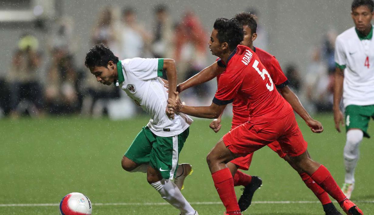 Pemain Indonesia U-23, Evan Dimas Darmono (kiri), berebut bola dengan pemain Singapura U-23. (Bola.com/Arief Bagus)