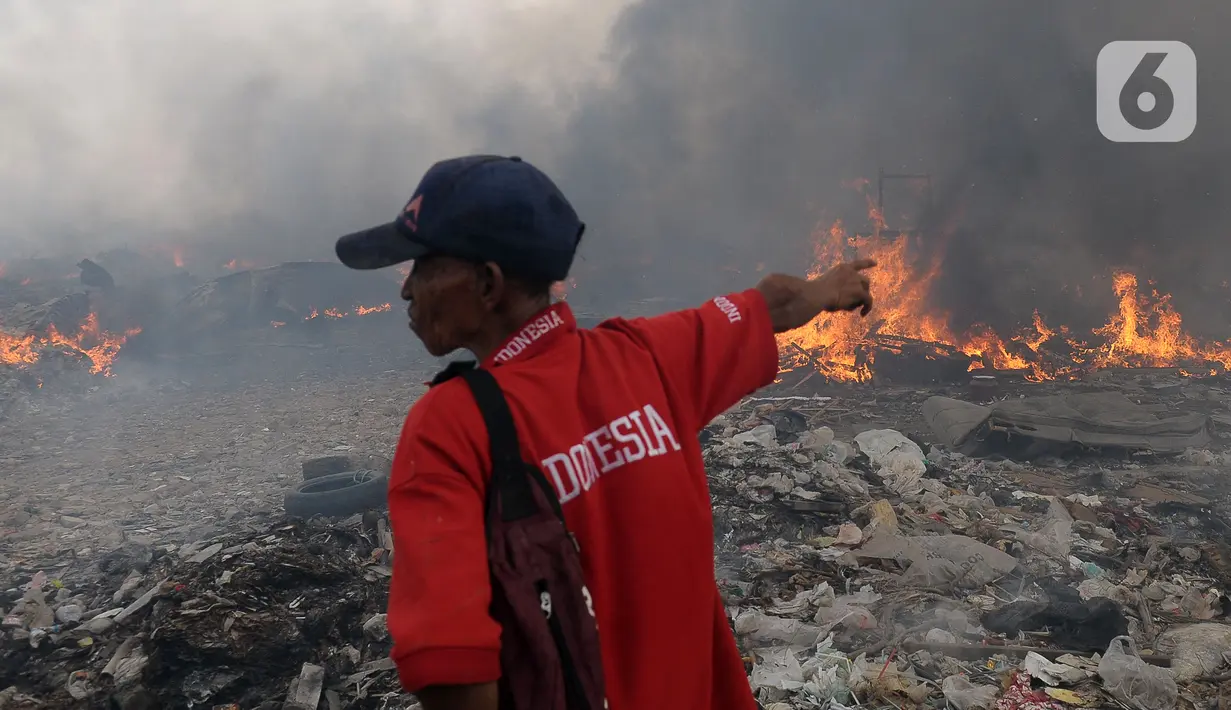 Seorang pria menunjuk ke arah api yang membakar rumah semi permanen dan lapak barang bekas di Bintara Jaya, Bekasi, Jawa Barat, Kamis (21/9/2023). (merdeka.com/Imam Buhori)