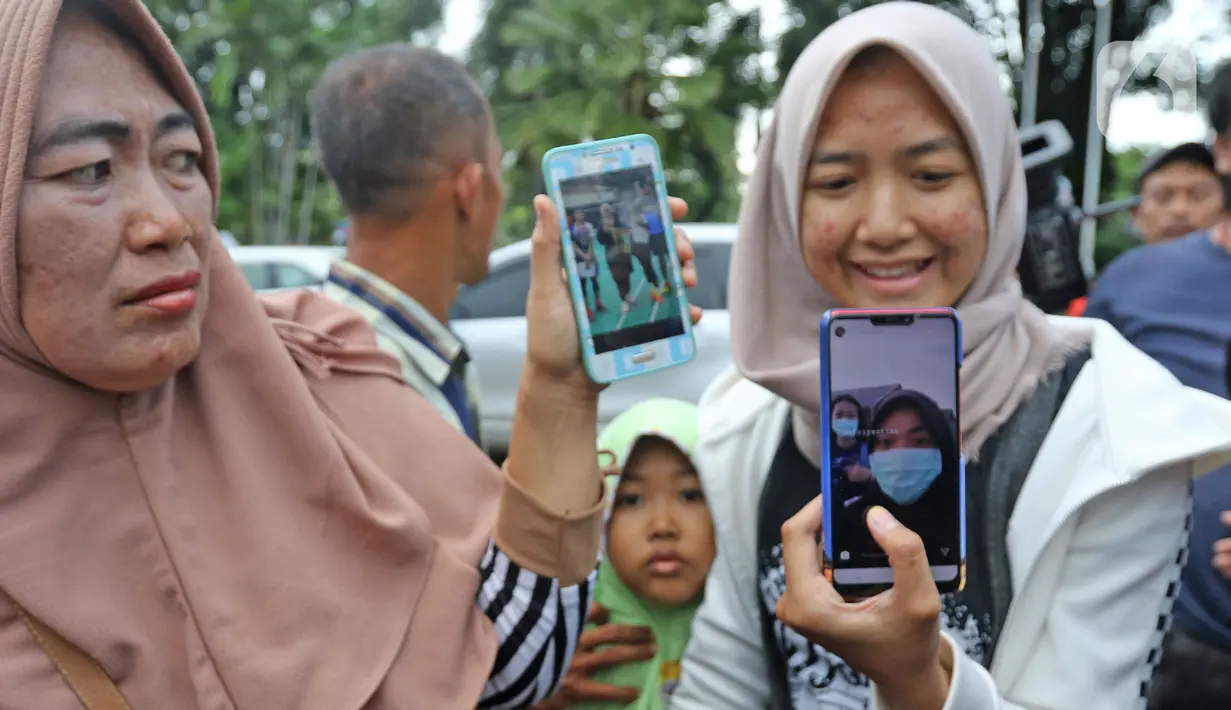 Pihak keluarga menunjukan WNI yang dievakuasi dari Wuhan, China saat menunggu di Bandara Halim Perdana Kusuma, Jakarta, Sabtu (15/2/2020). Pemerintah secara resmi memulangkan 238 WNI ke daerah masing-masing seusai menjalani observasi selama 14 hari di Ranai, Natuna. (Liputan6.com/Herman Zakharia)