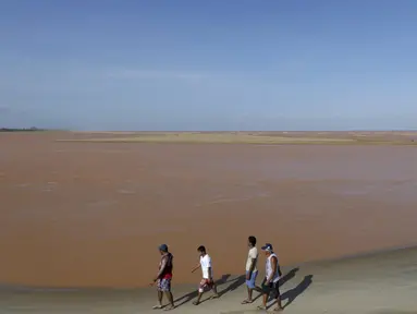 Pengunjung berjalan dipinggir pantai laut Espirito Santo yang airnya berubah menjadi cokelat di Brasil (22/11). Warna air berubah cokelat karena tambang milik Vale SA dan BHP Billiton jebol dan menumpahkan lumpur. (REUTERS/Ricardo Moraes)