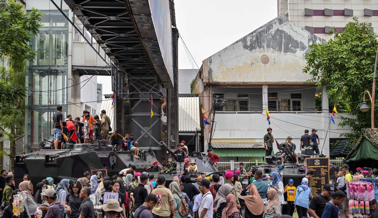 Berbagai kendaraan tempur milik Korps Marinir TNI AL dipamerkan di Jalan Gubernur Suryo, di depan Gedung Negara Grahadi. Tampak dalam foto, warga berfoto bersama kendaraan militer selama Pameran Marinir Indonesia, yang menandai peringatan Hari Ulang Tahun ke-80 Korps Marinir TNI AL di Surabaya, Jawa Timur pada Minggu 9 November 2025. (JUNI KRISWANTO/AFP)