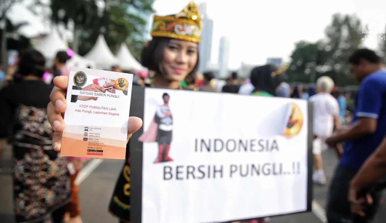 Satgas saber pungli menunjukkan buku imbauan saat mensosialisasikan tolak pungli di Car Free Day, Jakarta, Minggu (12/11). Satuan tugas sapu bersih pungutan liar (saber pungli) terus gencar melakukan sosialisasi anti pungli. (Liputan6.com/Faizal Fanani)