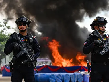 Petugas polisi militer Kamboja berjaga di depan tumpukan narkoba yang terbakar selama upacara penghancuran untuk memperingati "Hari Internasional Melawan Penyalahgunaan Narkoba dan Perdagangan Gelap" di Phnom Penh pada 28 Juni 2023.
(AFP/TANG CHHIN SOTHY)