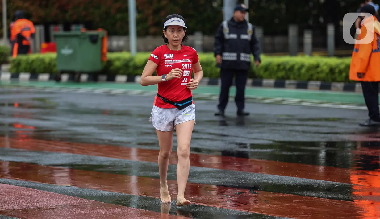 Seorang perempuan berolahraga di tengah rintik hujan pada Car Free Day atau hari bebas kendaraan di kawasan Bundaran Hotel Indonesia (HI), Jakarta, Minggu (12/2/2023). Hujan yang mengguyur Ibu Kota sejak malam sampai pagi ini tak menyurutkan semangat warga untuk tetap berolahraga di area CFD. (Liputan6.com/Johan Tallo)