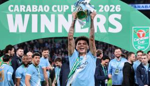 Nico O'Reilly mengangkat trofi Carabao Cup usai Manchester City mengalahkan Arsenal di partai final dengan skor 2-0. Pada laga ini ia membukukan dua gol. (Adrian DENNIS / AFP)