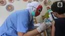 Tenaga kesehatan bertopeng superhero menyuntikkan vaksin covid-19 kepada seorang anak saat melayani vaksinasi anak usia 6-11 tahun di RSIA Tambak, Jakarta, Rabu (22/12/2021). Sebanyak 30 anak mengikuti vaksinasi yang menggunakan vaksin Sinovac tersebut. (Liputan6.com/Herman Zakharia)