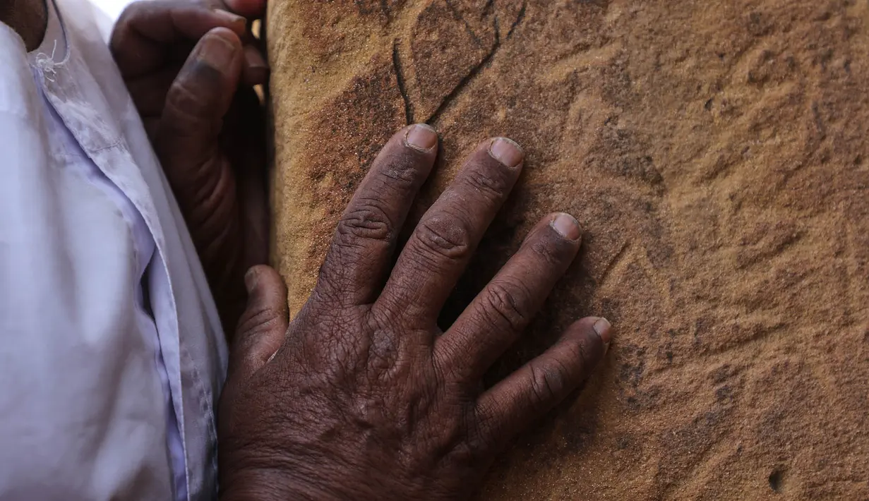 Seorang pengunjung menyusurkan tangannya pada blok-blok batu sebuah piramida di situs arkeologi Meroe di Bejrawiya, Sudan, Minggu, 2 Agustus 2026. (Foto AP/Mohnd Blal)